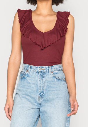 Burgundy ribbed bodysuit with a V-neck and ruffled neckline, paired with high-waisted light blue denim jeans.