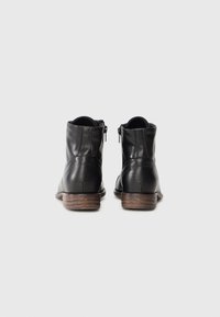 Botas de tobillo de cuero negro con un acabado texturizado, cremalleras laterales y un tacón de madera marrón, con un diseño de punta redonda y costuras mínimas.