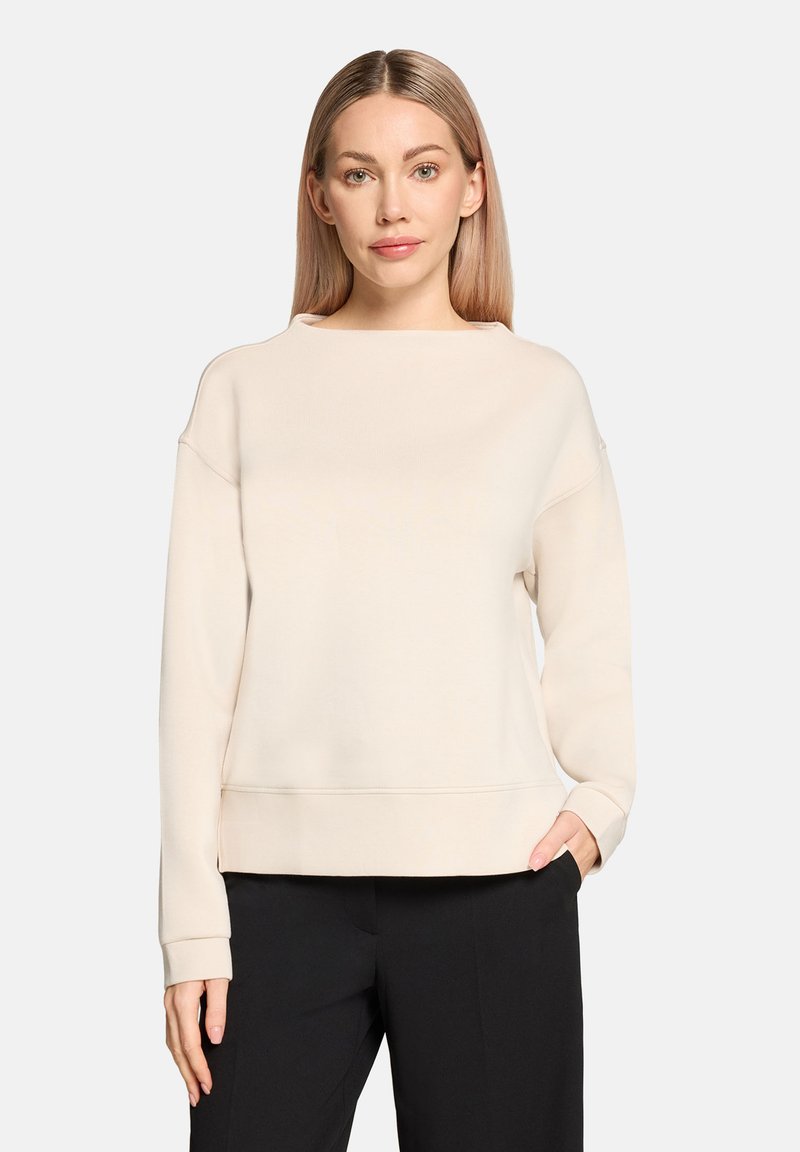 Sweat-shirt beige clair en tissu doux avec un large col et des épaules tombantes. Présente une coupe décontractée et des poignets côtelés.
