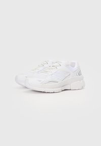 Hvite joggesko med mesh og syntetisk overdel, avrundet tå, polstret krage og teksturert gummisåle. Har minimalistisk design og subtile detaljer.