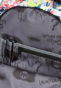 Wnętrze plecaka, szara tkanina z czarnymi wzorami Batmana i znaków zapytania. Posiada kieszeń na zamek i wiele przegródek do organizacji.