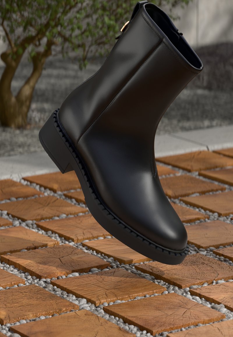 Stivaletto in pelle nera con finitura liscia, tacco a blocco basso e cuciture dettagliate, sospeso sopra una superficie in legno текстurizzata.