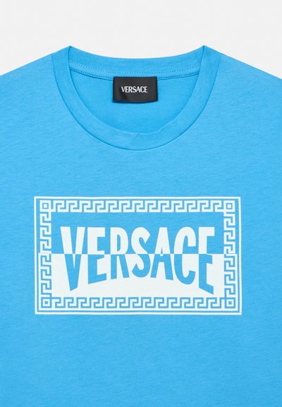 Cămașă cu guler rotund, albastru strălucitor, cu un logo Versace alb dreptunghiular încadrat de un model cheie grecească pe piept.