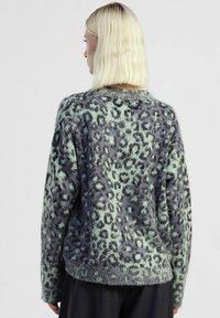 Maglione oversize in maglia morbida, caratterizzato da una stampa leopardo verde menta e grigia, con polsini e orlo a costine, e scollatura rotonda.