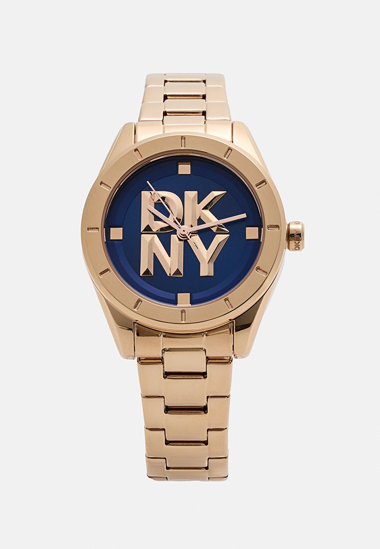 Złoty zegarek na stalowej bransolecie z niebieską tarczą, dużym logo DKNY i designem w postaci ogniw. Posiada geometryczne oznaczenia godzin i różowe wskazówki.