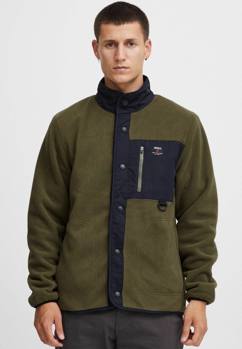 Fleece jacket in olive green with navy accents, featuring a snap closure, zippered chest pocket, and side pockets. Smooth texture with a casual fit.