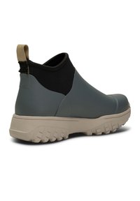 Bottine à enfiler grise et noire avec semelle beige texturée et tirant beige à l'arrière.