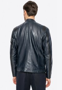 Giubbotto in pelle blu navy con una texture liscia, caratterizzato da accenti trapuntati sulle spalle e un design aderente. La vista posteriore mette in evidenza le cuciture delle spalle.