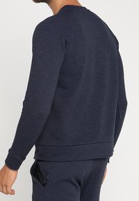 Sweat-shirt bleu marine en tissu texturé, avec manches longues, col rond et une coupe décontractée avec un ourlet et des poignets côtelés.