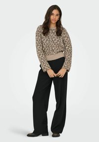 Beige leopardprint sweater med ribbet kant, parret med højwaist sorte vide bukser og sorte ankelstøvler.