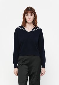 Pull-over en bleu marine avec un col en V et des détails de col rayé blanc, fabriqué à partir d'un matériau doux avec des manches longues.