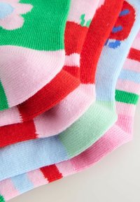 Bunte Strümpfe aus Strick mit Mustern von Blumen, Streifen und Blöcken in Grün, Pink, Rot und Blau, gefertigt aus strukturiertem Stoff.