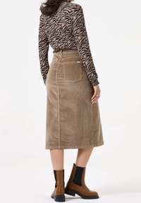 Brun manchesterkjol med bakficka, kombinerad med en långärmad svart och tan zebra mönstrad skjorta och bruna ankelstövlar.