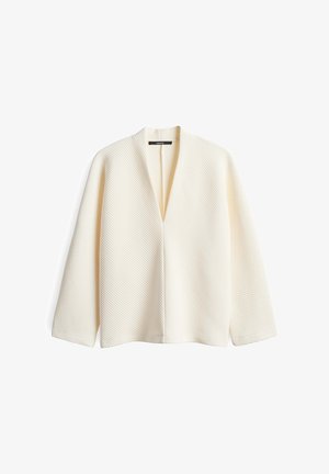 Veste blanche ouverte à l'avant avec un design texturé et côtelé, dotée de manches longues et d'une finition lisse. Style minimaliste sans embellissements.