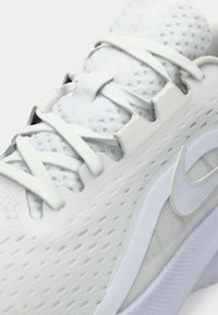 Λευκά αθλητικά παπούτσια από δίχτυ και συνθετικά υλικά, με υφή στο πάνω μέρος, επίπεδα κορδόνια και εμφανές λογότυπο στο πλάι.