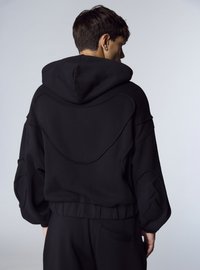 Felpa nera con cappuccio e schiena texturizzata, caratterizzata da maniche oversize e orlo a coste. Realizzata in materiale morbido e confortevole.