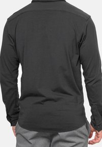 Mustapaita pitkähihaista, valmistettu pehmeästä kankaasta, jossa on napillinen kaulus ja suora helma, kalvosinvarret ja sileä pinta.