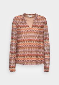 Blusa transparente com um padrão zigzag em tons de laranja, rosa e castanho, com um decote em V e colarinho e punhos com babados. Mangas longas.