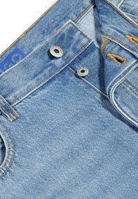 Jeans in denim azzurro chiaro con cuciture arancioni, bottoni in metallo argentato e una vita piegata che mostra il logo. Tessuto testurizzato con sbiaditure leggere.