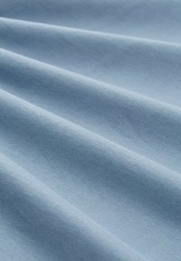 Himmelblaues Gewebe mit glatter Textur, das sanfte Falten und einen dezenten Glanz aufweist. Das Material scheint weich und fein gewebt zu sein.