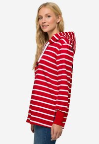 Felpa con cappuccio a righe rosse e bianche, dal fit rilassato, con maniche lunghe, spacchi laterali e coulisse regolabile sul cappuccio.