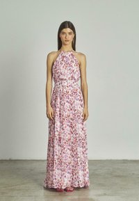 Vestido maxi tipo halter en tejido ligero, con un estampado floral en tonos rosa y púrpura, cintura ceñida con un cinturón y falda fluida.