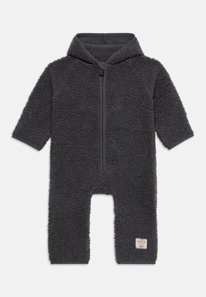 Mørkegrå babydragt med hætte, lange ærmer, lynlås foran, tekstureret fleece-stof og et lille hvidt mærke på venstre ben.