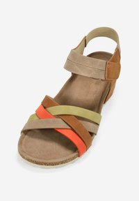 Sandalia marrón con múltiples correas en verde, naranja y marrón. Textura de suave ante, suela plana, correa ajustable en el tobillo y acento de corcho.