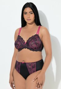 Zwarte kanten beha en bijpassende slip met hoge taille. De beha heeft roze accenten, geschulpte randen en verstelbare bandjes. De slip heeft kanten inzetstukken.