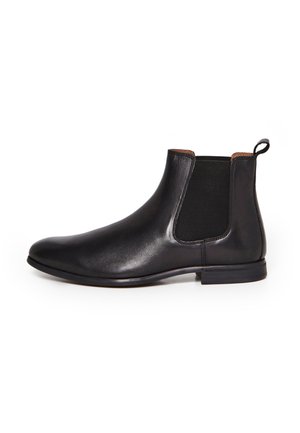 Botte Chelsea en cuir noir avec panneau latéral élastique, languette de traction au talon et petit talon empilé, vue de profil sur fond blanc.