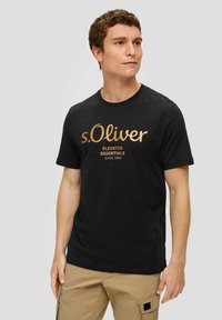 Schwarzes Baumwoll-T-Shirt mit rundem Ausschnitt und kurzen Ärmeln, mit goldbedrucktem Text "s.Oliver Elevated Essentials Seit 1969."