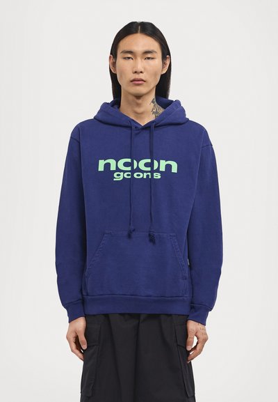 Dunkelblaues Hoodie mit einer vorderen Kängurutasche, das über ein großes grünes "noon goons"-Logo verfügt. Verstellbare Kordeln und gerippte Manschetten runden das Design ab.