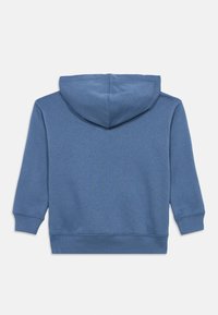 Μπλε φούτερ με κουκούλα και υφή υφάσματος. Διαθέτει μακριά μανίκια, χαμηλή πλάτη και μανσέτες και τελείωμα με ριμπ ύφασμα. Χωρίς εμφανή γραφικά σχέδια.