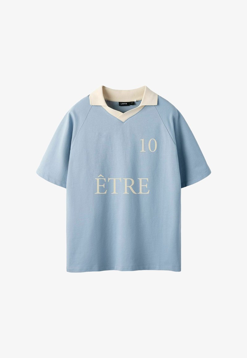 Chemise bleu clair à manches courtes avec col crème, "10" imprimé en haut à droite, et "ÊTRE" centré sur le devant en lettres crème.