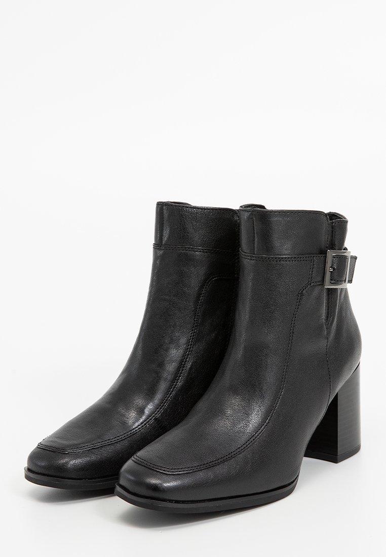 Bottes chelsea en cuir noir avec un bout carré, un talon block haut et un détail de boucle sur le côté. Texture lisse et accents de couture minimaux.