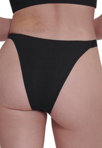 Zwarte katoenen bikini-broek met hoge zijkanten en minimale achterkantbedekking. Gladde textuur met een naadloos ontwerp, voorzien van een zachte tailleband.