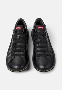 Sneakers in pelle nera con una superficie liscia, punta arrotondata e sei stringhe nere prominenti. Presentano un logo rosso Camper sulla linguetta.
