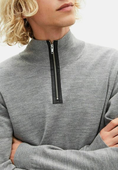 Grijze gebreide pullover met een hoge kraag en zwarte ritssluiting, met een zachte textuur en lange mouwen. Minimalistisch ontwerp zonder patronen.