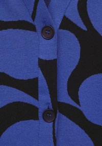 Svetr v modro-černém vzoru s pletenou texturou, V-výstřihem a černými knoflíky vpředu.