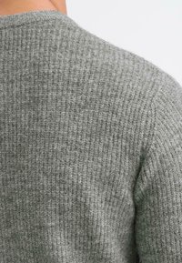 Hallitusestatud hall villane sviiter tekstuurse ribakujundusega. Omab ümmargust kaelust ja pehmet, sooja kangast, sobib igapäevaseks kandmiseks.