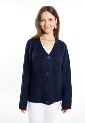 Tummansininen neulottu cardigan, jossa on V-pääntie, viisi suurta sinistä nappia edessä sekä pitkät hihat, valmistettu teksturoidusta kankaasta.
