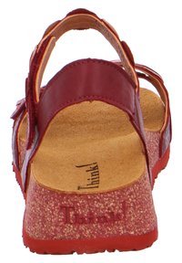 Red leather sandal with a cork footbed, adjustable straps, and textured outsole. Features a cushioned insole for comfort.