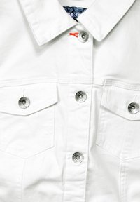 Chaqueta de denim blanca con botones a presión plateados, dos bolsillos en el pecho y costuras en contraste. Tejido texturizado con un diseño limpio y moderno.