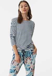Gestreept lang mouwtop in marineblauw en wit katoen, gecombineerd met lichtblauwe broek met een bloemendessin in roze en marineblauw. Koord aan de taille.