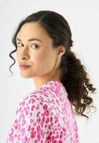 Korte mouw top in het wit, met een roze luipaardprint. De stof lijkt glad, met een ronde halslijn en een ontspannen pasvorm.