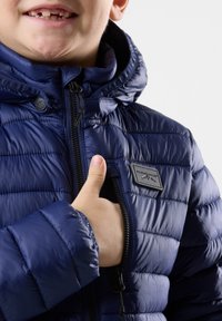 Merijalan puffer jakki dengan penutup zipper di depan, jahitan tekstur, dan label merek yang mencolok di dada. Tudung yang dapat disesuaikan dengan manset elastis.