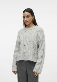 Maglione grigio lavorato a maglia con motivo a treccia e punti aperti. Vestibilità rilassata, polsini a coste e scollatura rotonda abbinati a pantaloni grigi.