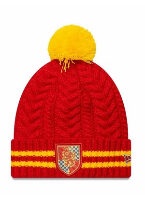 Red knitted beanie with a yellow pom-pom on top, featuring a ribbed band with two horizontal yellow stripes and a crest on the front.