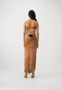 Takaa katsottuna virtaava, läpikuultava ruskea-oranssi maxi-mekko, jossa on herkät olkaimet ja avoin selkä, ja jossa on abstrakteja kukkakuoseja.