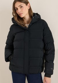 Doudoune noire avec capuche, dotée d'une fermeture éclair, de coutures horizontales, de poches latérales et d'un détail de logo sur la manche.